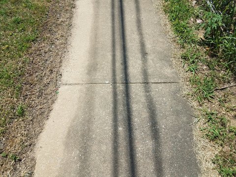 Shadows Of Overhead Power Lines On Grey Cement Sidewalk