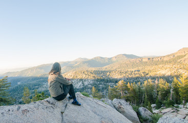 Girl Sitting on Rock Looking at Vista of Mountain 