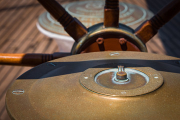 Antique brass compass on tiller of sailing ship 