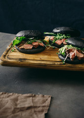Three black burgers with beef steak dark background