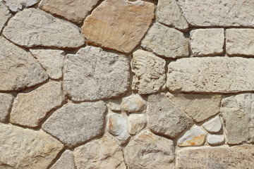 Ancient medieval stone masonry. Texture of a fragment of a wall of an old structure. A background for design and creative work. Decoration and exterior decoration of the building. Construction works. 