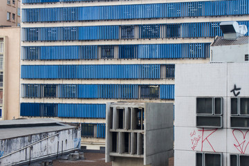 Blue windows building facade with old and graffiti painted buildings on front of it in downtown