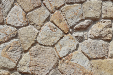 Ancient medieval stone masonry. Texture of a fragment of a wall of an old structure. A background for design and creative work. Decoration and exterior decoration of the building. Construction works. 