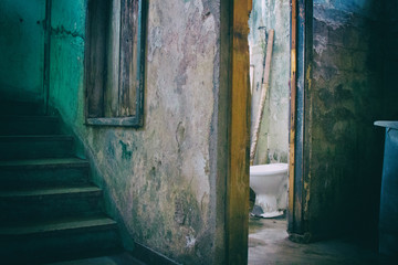 Open bathroom door near a staircase in an eroded abandoned building used by social housing movement as home by poor people. Brazil. South America. No people.