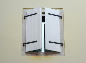 Beautiful old window frame with white wooden shutters and pale white wall.  Rural antique window frame. Design element. Template or mock up. 