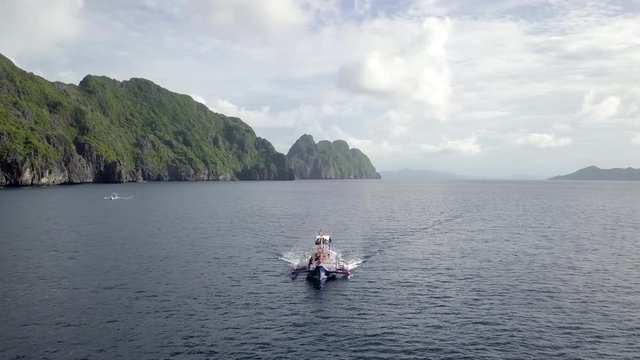 Boat cruising the island paradise of El Nido Palawan Philippines on calm blue sea on a perfect day