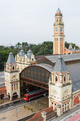 Fototapeta na wymiar View from a high angle of a train station with a tall clock tower with a red train departing. Brazil. South America. No people.