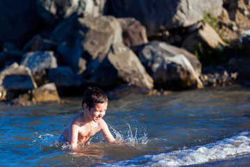 Happy boy swimming and playing in the sea. Kids having fun outdoors. Summer vacation and healthy lifestyle concept.