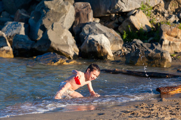 Happy boy swimming and playing in the sea. Kids having fun outdoors. Summer vacation and healthy lifestyle concept.