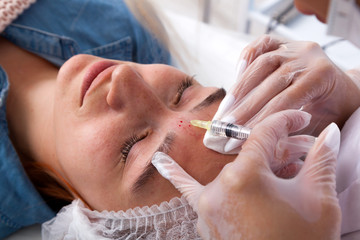 The doctor cosmetologist makes the Rejuvenating facial injections procedure for tightening and smoothing wrinkles on the face skin of a beautiful, young woman in a beauty salon.Cosmetology skin care.