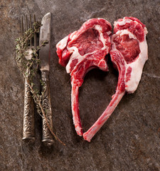Raw lamb chops with thyme on a gray stone background