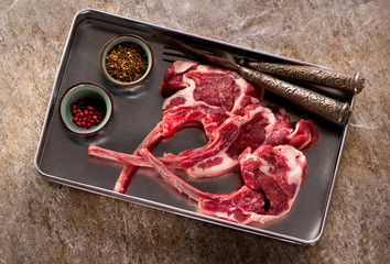 Raw lamb chops with herbs and spices on a gray stone background