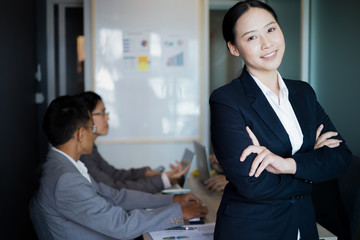 Young businesswoman with crossed arms standing near the office window, business concept