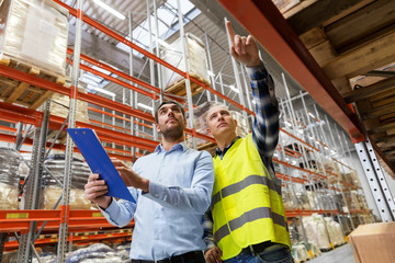Obraz premium wholesale, logistic business and people concept - manual worker and businessman with clipboards at warehouse