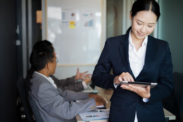 Young businesswoman standing with tablet near the office window, business concept