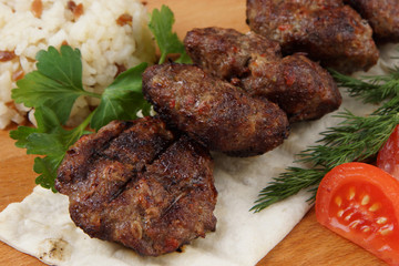 Fried cutlets lie on pita bread with vegetables and greens