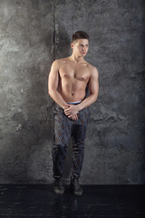 Obraz na płótnie Canvas Portrait of strong healthy handsome Athletic Man Fitness Model posing near dark gray wall