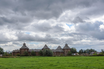 A complex of buildings in the style of a medieval wooden fortress. Cloudy weather, rain, storm clouds.