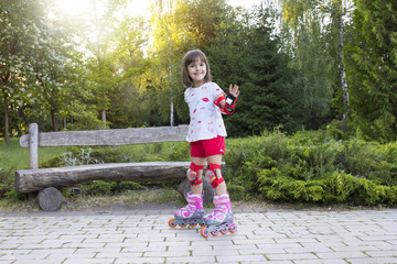 A little girl is rollerblading. In the open air in the park.