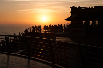 Silhouette of people looking at the sunset from a deck in front of the ocean. Beautiful wallpaper.