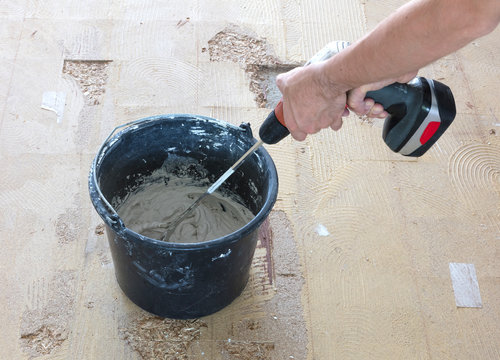 Man Is Mixing Grey Concrete And Prime In The Bucket.