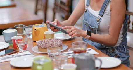 Woman take photo of the cake in coffee shop