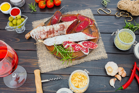 Sliced cured sausage and bresaola with spices and a glass of red wine.