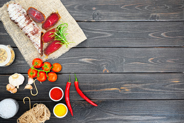 Sliced cured bresaola with spices and a sprig of rosemary.