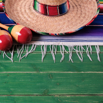 Mexico cinco de mayo fiesta carnival traditional green wood background border mexican sombrero maracas and serape rug or blanket photo square format