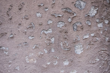 Wallpaper texture of worn concrete wall colored in salmon paint with decayed peeling plater. No people.