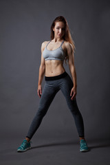 Sporty and sexy slim girl posing on grey background