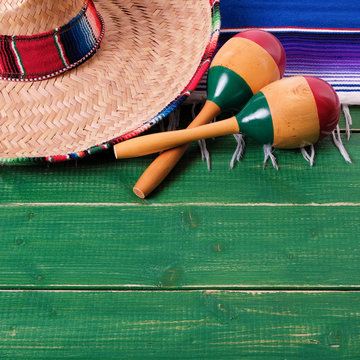 Mexico cinco de mayo fiesta carnival traditional green wood background border mexican sombrero maracas and serape rug or blanket photo square format