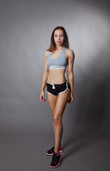 Fototapeta premium Sporty and sexy slim girl posing on grey background