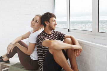 Obraz premium Happy girl and guy, cute couple looking out the window in their new home