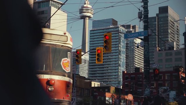 Camera tracks from behind a person to reveal a busy intersection with the CN Tower in the background in Toronto