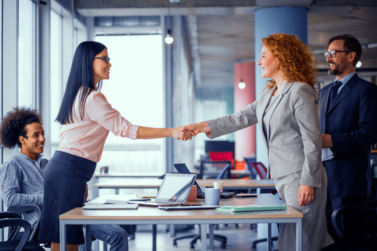 Working space. Two businesswomen shaking hands. Deal between two business teams. Toned concept.