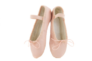 isolated pair of beginner ballerina shoes placed on tiptoes / pink baby shoes for learning to dance