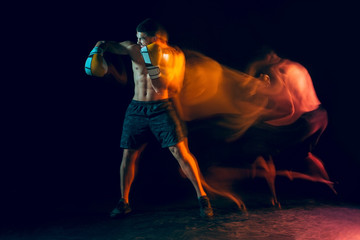 Male boxer boxing in a dark studio