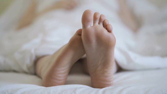Woman in bare legs and feet on the bed