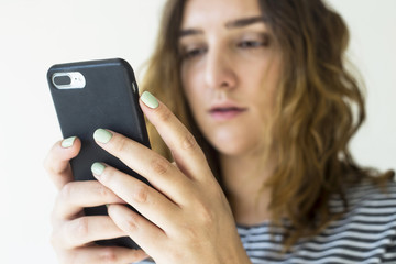 A girl is holding a smartphone and looking at the screen. Technology and online life