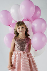 smiling little kid looking at camera and holding bunch of air balloons