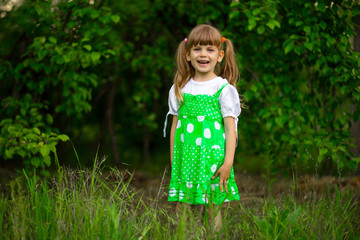 Little girl walk in green garden in sunny summer day