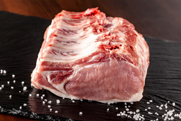 Raw meat pork. Tenderloin on the bone. ribs. on a black background. salt on the table.
