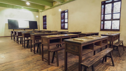 Wide Angle Shot of A Traditional Asian Class Room Environment with Wooden Desks / Tables, Bench / Chair and Blackboard.
