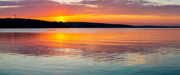 Fototapeta na wymiar Gorgeous orange teal sunset on huge calm lake