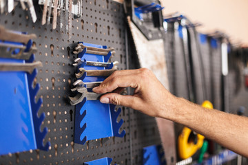 Obraz premium Close up man hand choosing wrenches in workshop isolated