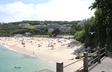 Fototapeta na wymiar Holidaymakers and sunbathers on Newquay beach with azure seas. Newquay, Cornwall, UK