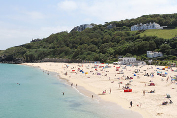 Holidaymakers and sunbathers on Newquay beach with azure seas. Newquay, Cornwall, UK
