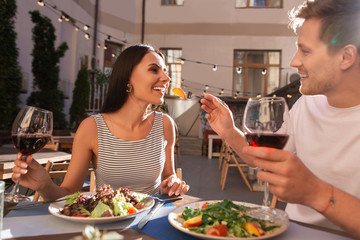 Wine evening. Dark-haired appealing woman feeling satisfied and relaxed while drinking red wine with her man