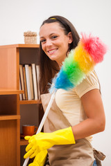 Young happy woman is cleaning the furniture in the house.